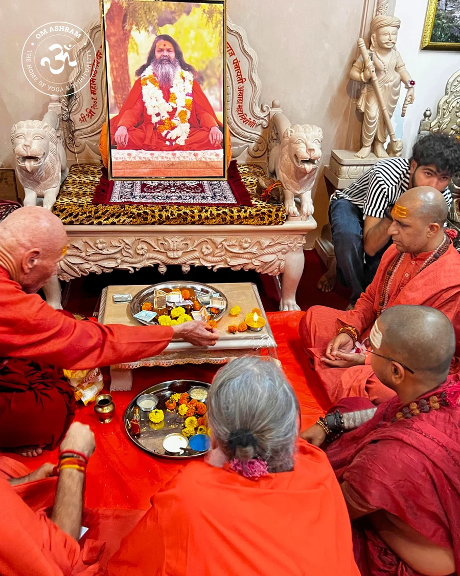 A traditional puja thali with flowers and lamps before the gadi of Gurudev.